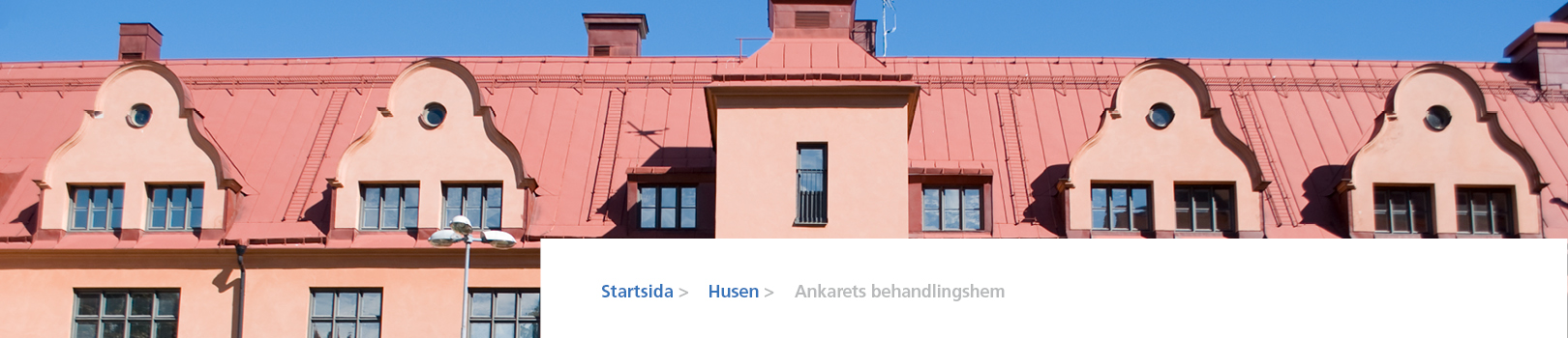 Fasad på Grimmans aprikosfärgade byggnad och orange plåttak.
