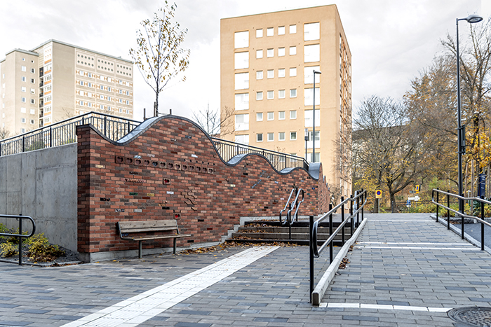 Återställande Kraft 2019 ©Lillemor Petersson. En mur av tegel på vänster sida om en gångväg med stenplattor.