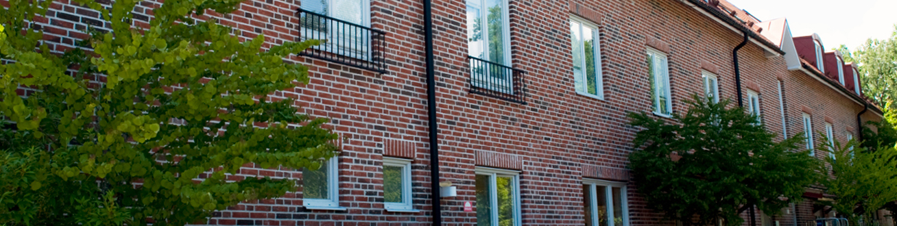 Tegelbyggnad med orange tak och flera träd kring byggnaden. 