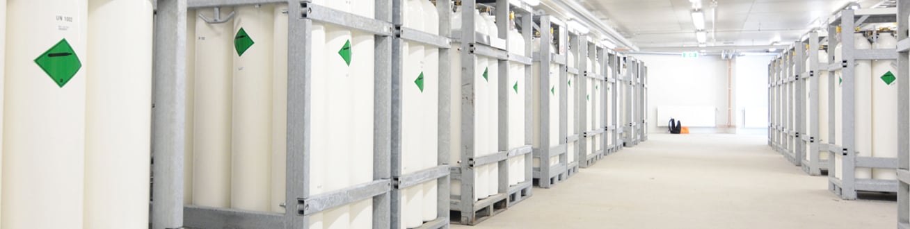 Vita gastuber står uppradade i metallbehållare i stort rum.