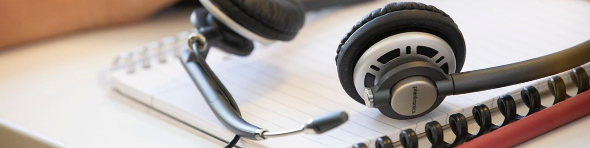Hörlurar som ligger på några utskrivna papper. 