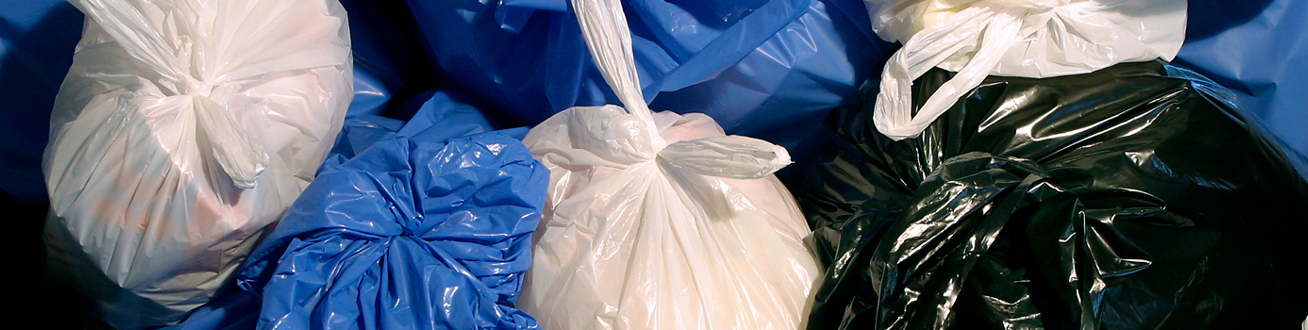 Flertal vita, blå och svarta stora fyllda sopsäckar som ligger tillsammans. 