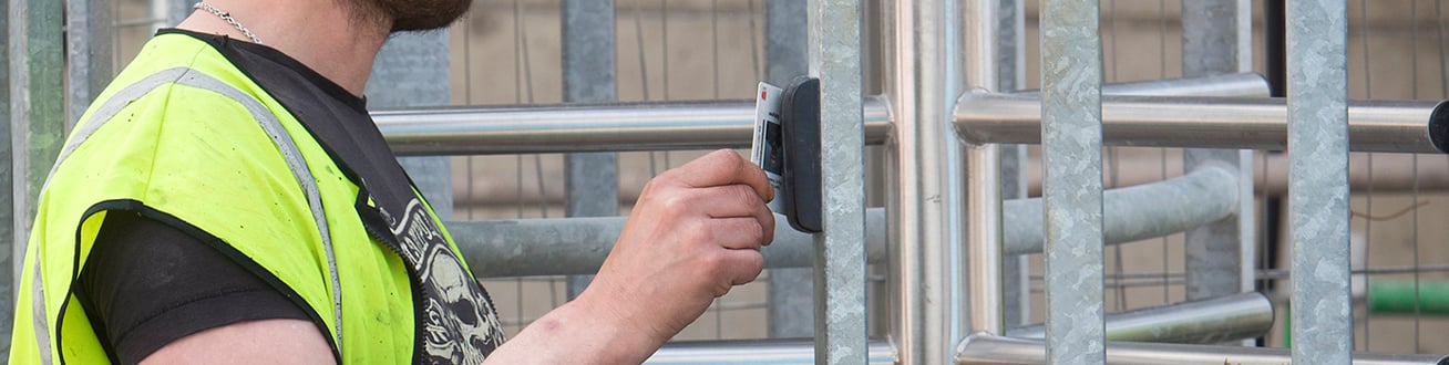 En man i gul varselväst som håller fram sitt kort mot en kortläsare.