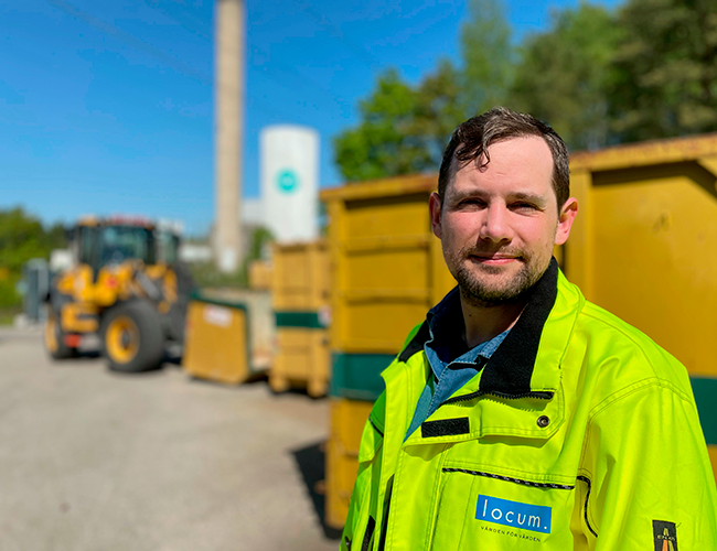 En man i en varseljacka som står framför en container.