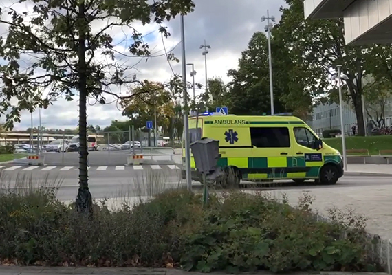 Ambulans som kör förbi akutvårdsbyggnad vid Danderyds sjukhus.