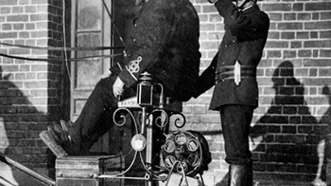 Historisk svartvit bild på tre brandmän. 