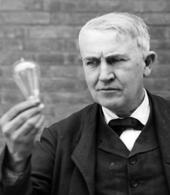 Svartvitt foto av Thomas Edison som håller i en glödlampa.