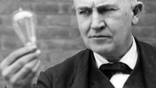Svartvitt foto av Thomas Edison som håller i en glödlampa.