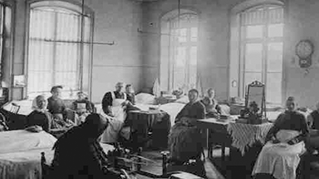 Historiskt svartvitt foto av patienter och vårdpersonal i en stor vårdsal.