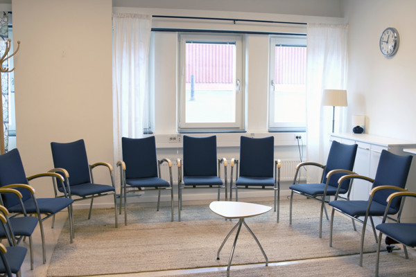 Kontorsrum med flera klädda stolar bredvid varandra utmed väggen.