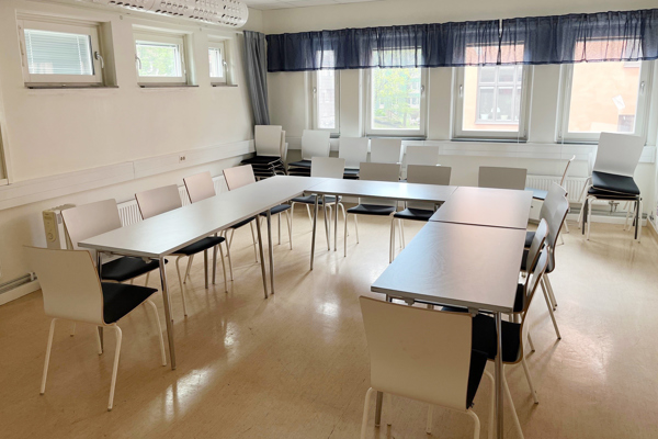 Konferensrum i äldre stil med vita möbler i u-form.