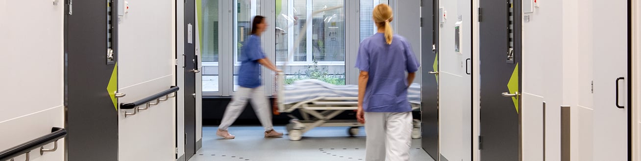 Sjukårdspersonal på avstånd går i sjukhuskorridor