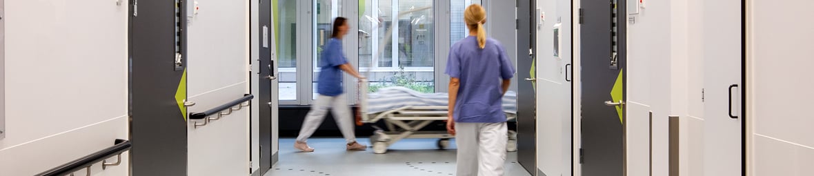 Sjukårdspersonal på avstånd går i sjukhuskorridor