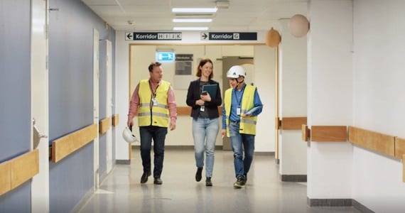 Fastighetsförvaltare och driftpersonal går tillsammans i korridor på sjukhus.