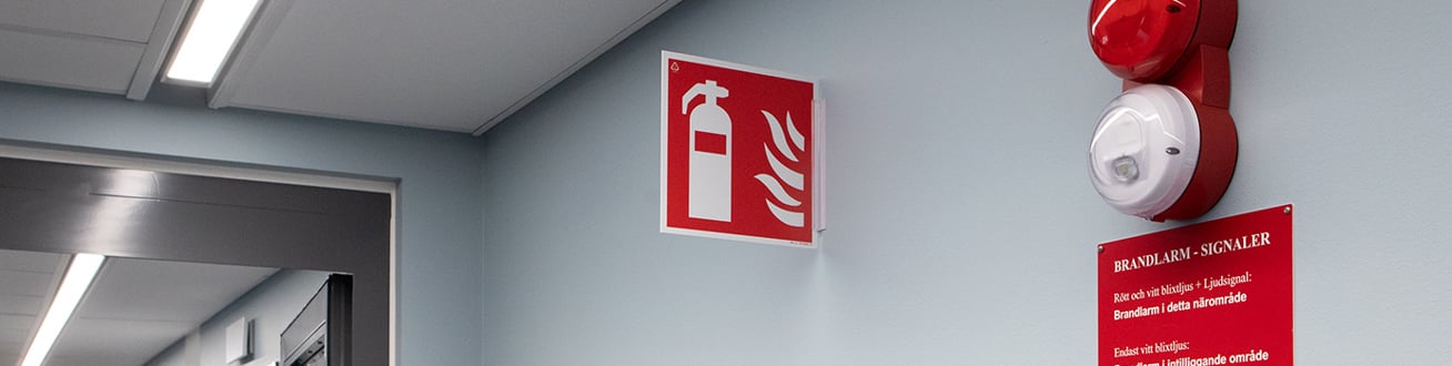 Brandlarm och brandskylt i korridor.