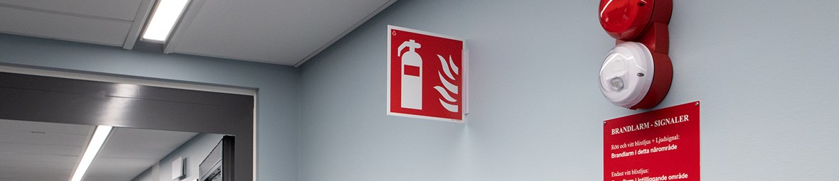 Brandlarm och brandskylt i korridor.