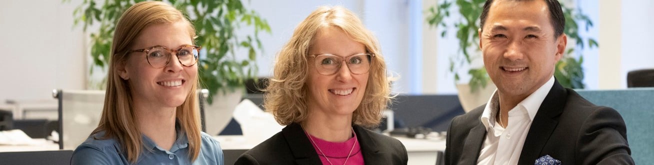 Tre medarbetare på Locum tittar in i kameran och ler.